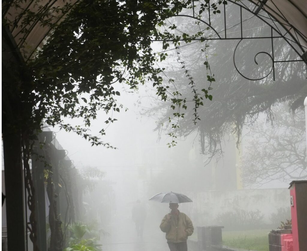 Pessoa entrando na Rua Coberta de Gramado, cidade com neblina.